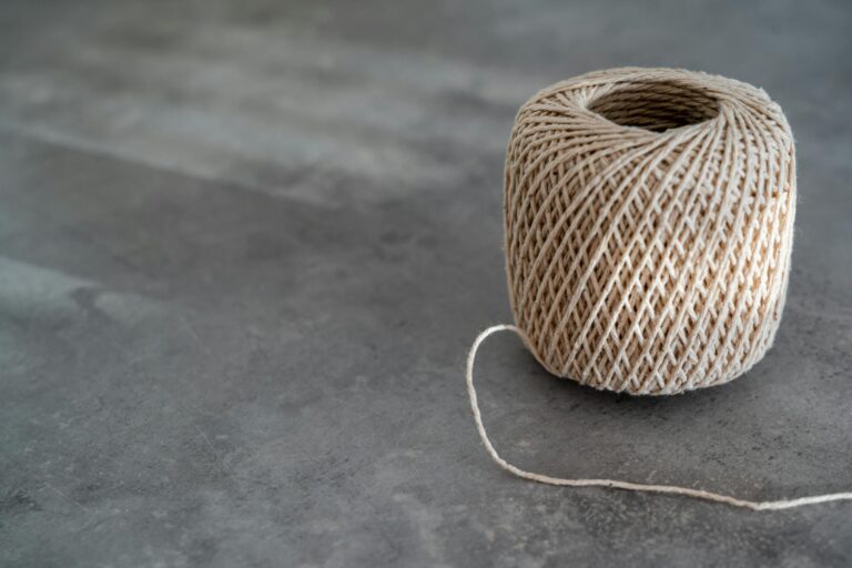 Close-up of a rustic spool of twine resting on a textured surface, perfect for crafts.