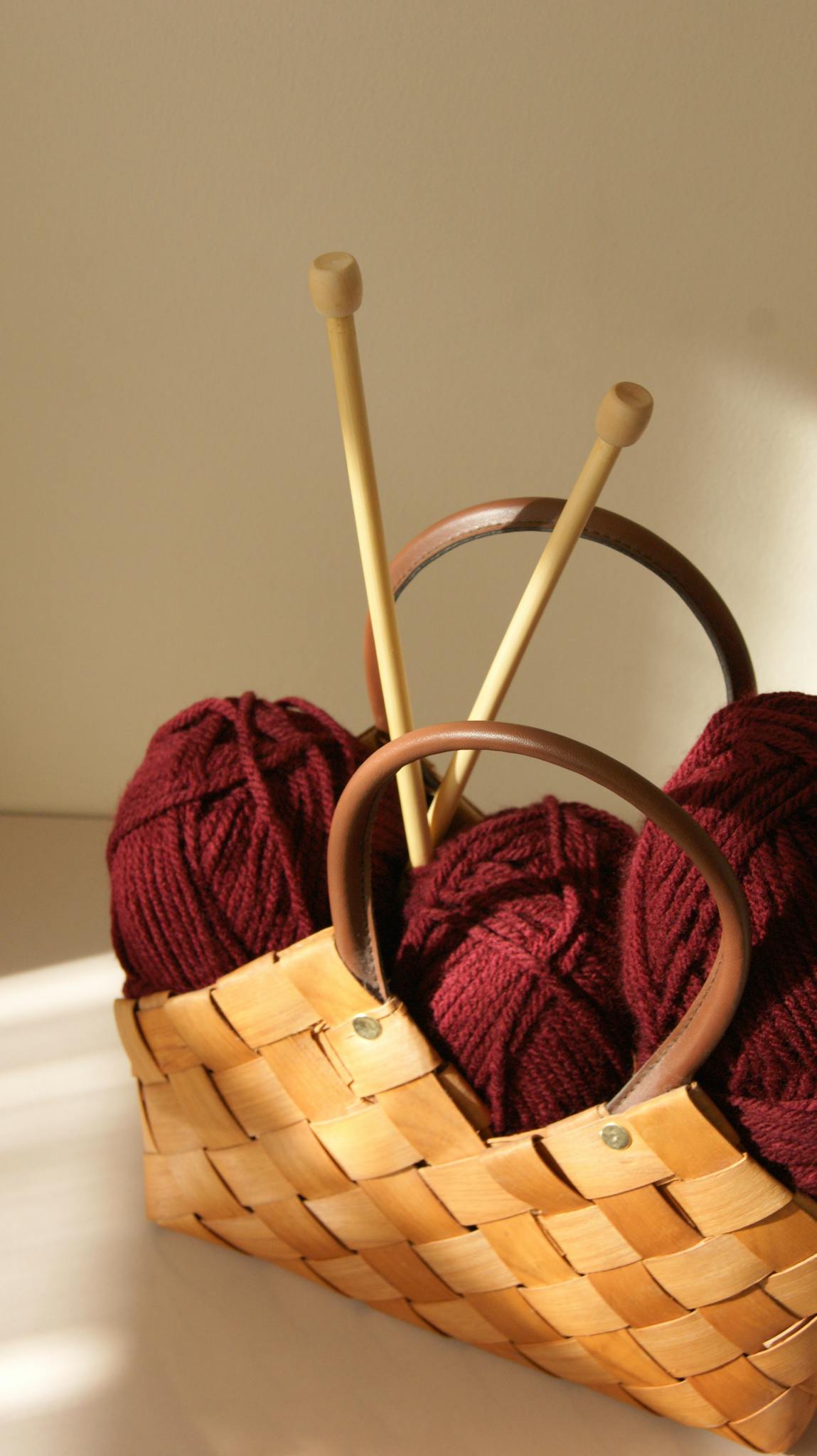 Warm sunlight on yarn and needles in a rustic basket, ideal for cozy craft themes.